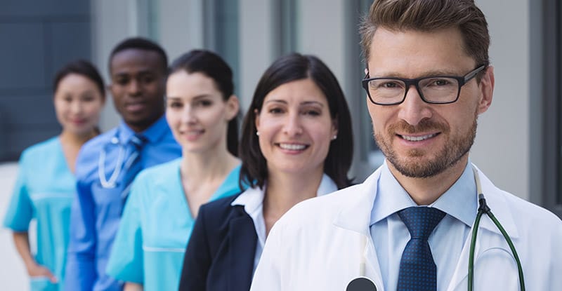 Portrait of smiling doctors standing in row at hospital premises
